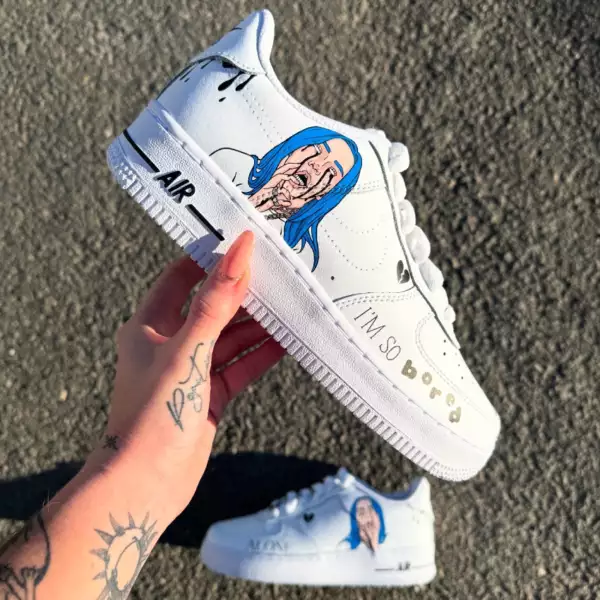 Nike Air Force 1 custom Billie Eilish avec portraits peints à la main en bleu sur les côtés externes, et inscriptions "I’m so bored" et "Alone" à l’avant des chaussures.